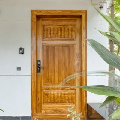 The main door at Villa 17, crafted from solid teak with carved details. It offers a warm and impressive welcome.