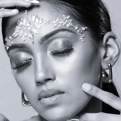 A stunning black and white beauty portrait focusing on a crystal headpiece and shimmering eyeshadow. The monochrome style enhances the texture and sparkle.