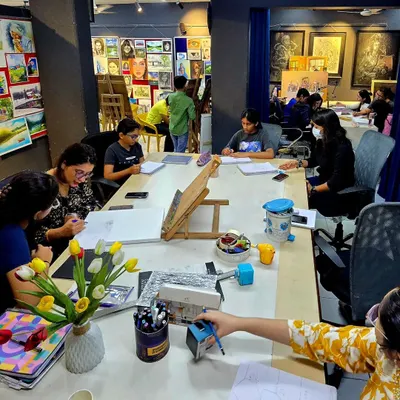 A wide view of a busy workshop session at our studio. Students are gathered around a large table, completely absorbed in their individual art projects.