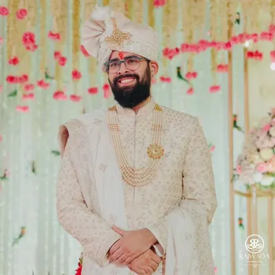 A happy groom on his wedding day, dressed in a classic ivory Shauhar sherwani. His smile says it all, a perfect picture of royal elegance and joy.