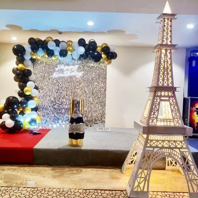 A chic Paris-themed birthday setup. This decoration combines a silver sequin backdrop and a black-and-gold balloon arch with our signature light-up Eiffel Tower prop for a touch of international glamour.