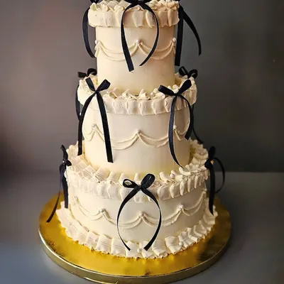 Vintage pro max! A stunning three-tier chocolate truffle cake in the Lambeth style, adorned with black ribbons for a chic and dramatic look.