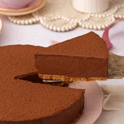 A perfect slice of my Belgian Chocolate Mousse Cake being lifted, showcasing its incredibly smooth and velvety texture against the crisp biscuit base.