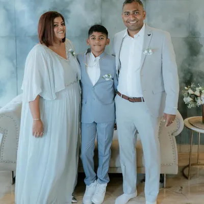 A beautiful family portrait in coordinated pastel tones. I designed the mother's flowing gown and the son's light blue suit to create a harmonious and picture-perfect look.