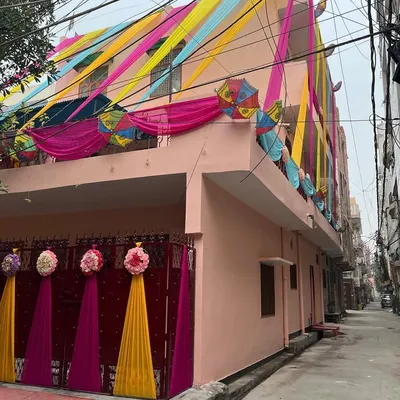 For this home wedding event, I transformed the entire house front with vibrant drapes in yellow, pink, and blue, along with decorative umbrellas and floral bunches on the gate.