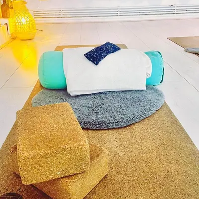 This is a typical setup for a restorative yoga session, with a bolster, blocks, and blankets ready. These props are essential for supporting the body, allowing for complete relaxation and release in poses held for several minutes.