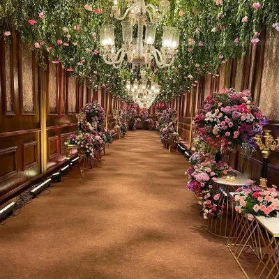 I designed this grand entrance to be an experience in itself. A long passage with rich, wood-paneled walls was transformed by a ceiling overflowing with fresh greenery and thousands of pink flowers, leading guests into a floral wonderland.