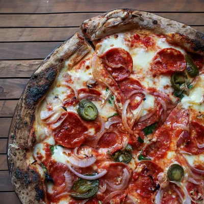 A close-up of our Diavola pizza. This one packs a punch with salty pepperoni, a trio of chilies for heat, and sweet onions to balance it all out on our signature sourdough crust.