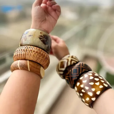 Stacking bangles is one of my favorite ways to accessorize. Here, I've mixed different wooden and resin bangles with various prints and textures to create a bohemian, Y2K-inspired look. It's all about playful layering.