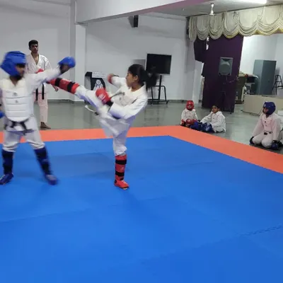 A student executes a high mawashi geri (roundhouse kick) during a kumite practice match. We focus on developing powerful and accurate kicking techniques for competition.