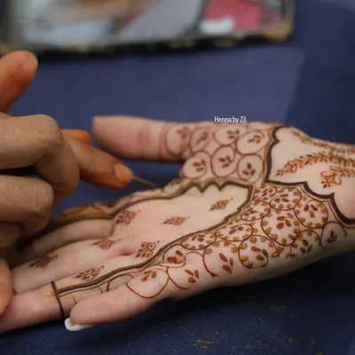 A close-up shot of me applying henna to a client's palm. You can see the fine lines and delicate floral details taking shape, a process that requires immense focus and a steady hand.