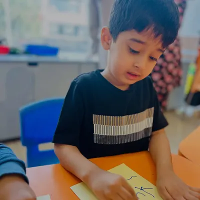 A young boy in our speech and drama class concentrates on writing or drawing, an activity that helps build the focus needed for performance and self-expression.