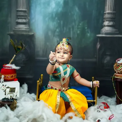 Our little Kanha in a classic pose. This image showcases the full Krishna setup with a divine backdrop, a pot of makhan, and the baby's playful expression.