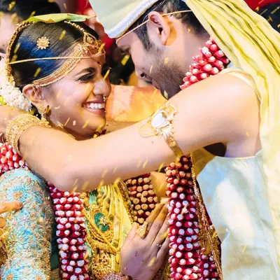 A candid, joyous moment from the Chola-inspired wedding. This captures the happiness of the couple during the ceremony, with a focus on the bride's radiant smile and traditional jewelry.