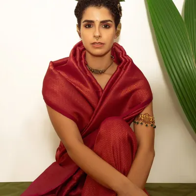 A portrait from a series that fused traditional Indian draping with minimalist, natural elements. The rich red of the fabric contrasts beautifully with the fresh green leaves used as a headpiece.