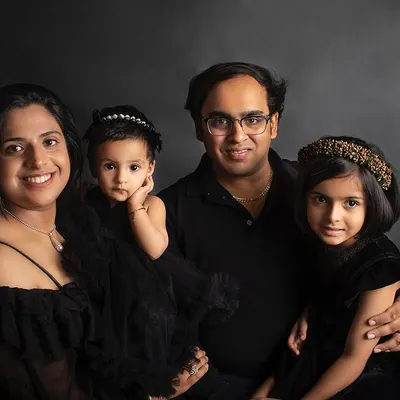 A classic and elegant family portrait against a dark backdrop. Coordinated black outfits create a timeless look that emphasizes their connection.