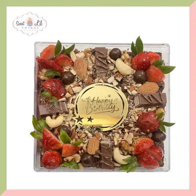 A custom "Happy Birthday" brownie box, fully loaded with a delicious mix of toppings. This shareable dessert features our fudgy brownies covered with fresh strawberries, whole almonds, cashews, and chunks of chocolate.
