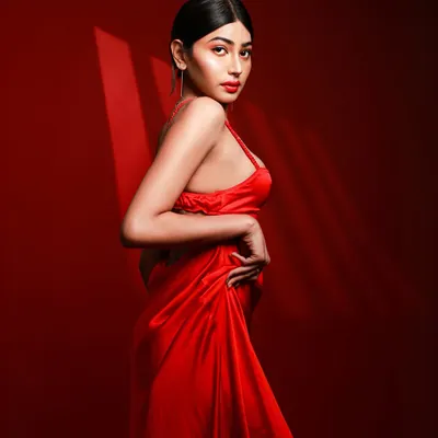 A model in a flowing red satin dress against a solid red background, with dramatic lighting creating shadows that accentuate her form. This is a perfect example of a monochromatic, high-impact studio shot.