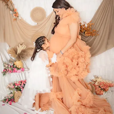 The sweetest kiss for a new sibling. A big sister-to-be gives a gentle kiss to her mommy's baby bump, a truly precious and heartwarming moment.
