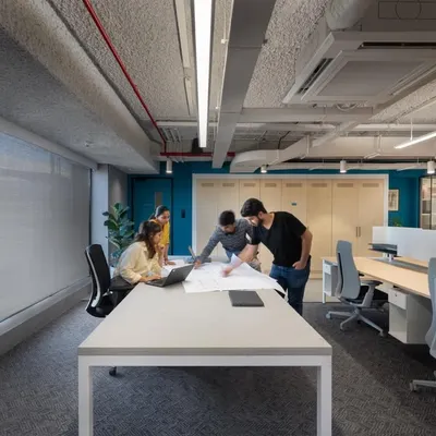 Collaboration is at the heart of our design process and the offices we create. This image shows a typical scene in a modern workspace we designed, with an open layout and large tables that encourage teamwork.