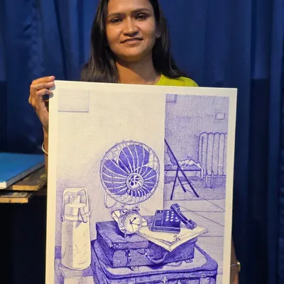 The proud moment of completion. One of our talented students displays her finished ballpoint pen still life, a complex scene rendered with impressive detail and shading.