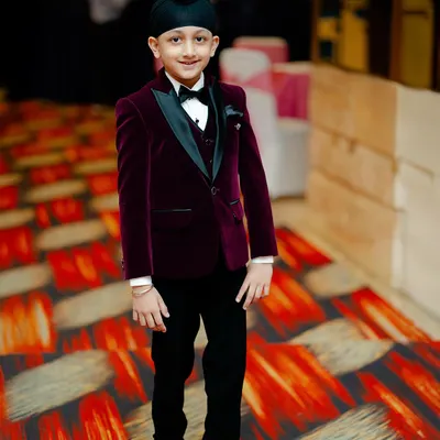 A picture of pure elegance. This young gentleman is ready for a wedding reception in our made-to-measure velvet tuxedo, featuring a satin lapel and a perfect fit that exudes class.