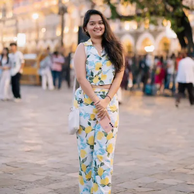 A bright and cheerful portrait taken in a busy plaza. Her lemon-print outfit and happy smile perfectly match the sunny day and lively background.