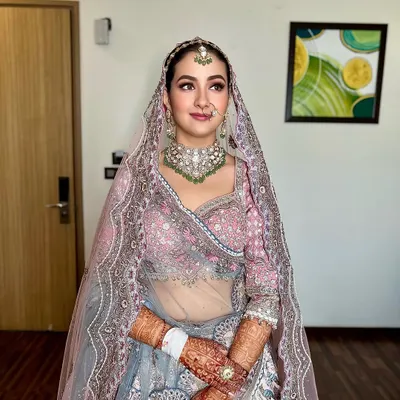 A beautiful bride ready for her wedding. The hair is styled in a clean, traditional updo, secured neatly under the dupatta and adorned with a maang tikka, creating a flawless and regal profile.