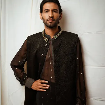 A strong, classic pose for a men's fashion portfolio. This shot highlights the elegant details of the embellished collar and the texture of the vest, creating a look of modern sophistication.