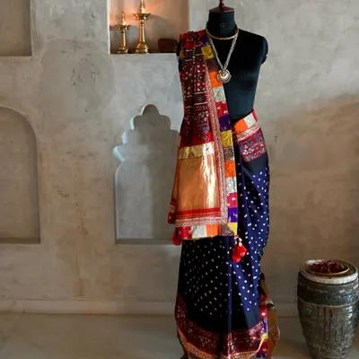 A full view of a bespoke saree, crafted from hand-dyed silk with Bandhni dots and an Ajrakh patchwork pallu. The piece is brought together with Zardozi embroidery and fragments of Banarsi fabric, creating a rich tapestry of Indian textile arts.