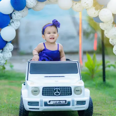 Making a grand entrance. This fun shot features a baby girl in a miniature Mercedes G-Wagon, part of a creative pre-birthday photoshoot with fun props.