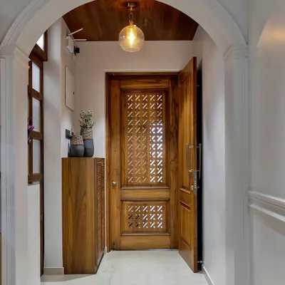 The beauty is in the details. This stunning entryway features an intricately carved wooden door, an arched passage, and warm pendant lighting, creating a grand and welcoming first impression.