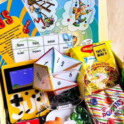 Our 90s Kid Nostalgia box is a blast from the past! It's filled with a brick video game, Poppins candy, Phantom cigarettes, a Tinkle comic, and a 'lattu' (spinning top).