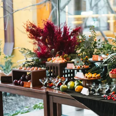A grand tapestry of flavor. This is a wide view of a grazing table designed by Chef Maxime Montay, featuring an extravagant spread of fruits, desserts, and savory bites set against our indoor-outdoor space.