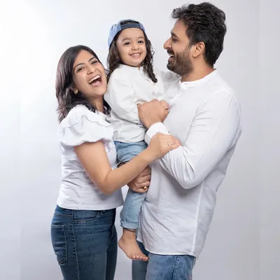 Laughter is the best accessory. This candid studio family portrait captures the pure happiness and love between parents and their child in a simple, classic setting.