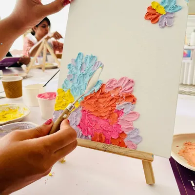 A close-up from one of our texture art experiences. Here, a participant is using a palette knife to create beautiful, pastel-themed floral textures on their canvas. I love seeing people discover their creativity.