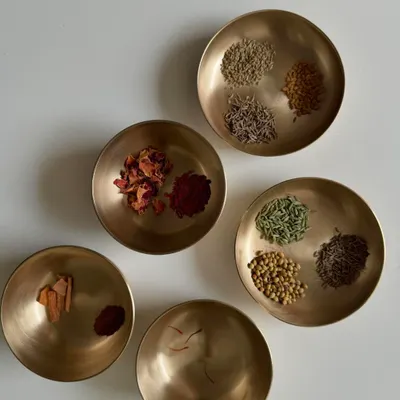 My art is rooted in a plant-based life. Here you can see various spices and dried flowers in brass bowls, which I use to create natural dyes and pigments. Each one offers a unique color and a connection to the earth.