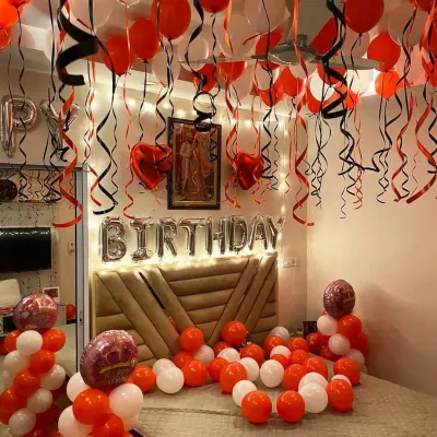 A classic birthday room decoration with red and white balloons covering the ceiling and floor, and 'BIRTHDAY' foil letters above the bed.