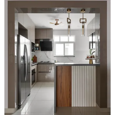 This open-concept kitchen features a pass-through view to the dining area, complete with a breakfast bar. The design uses a mix of wood and white fluted panels on the island, glossy beige cabinets, and a marble-finish backsplash.