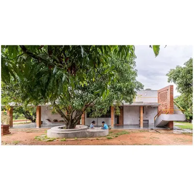 The 'Aamra' residence is designed around a majestic mango tree, which becomes a natural gathering spot. The structure's L-shape form creates a protective embrace around this central feature, integrating the home with the existing orchard.