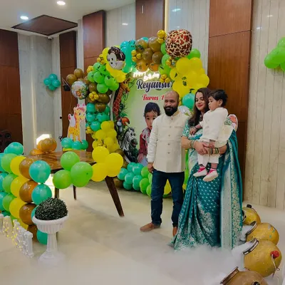 A jungle-themed first birthday party setup, complete with a green and yellow balloon arch, animal cutouts, and a low-lying fog effect for a magical touch.