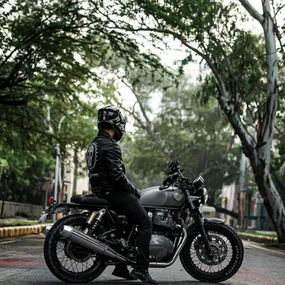 A full shot of the Royal Enfield Interceptor 650 on a tree-lined road. The composition and moody color grading create a classic, timeless feel that aligns with the brand's heritage.