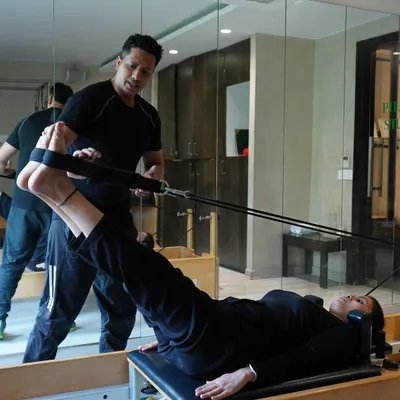 I believe in hands-on guidance. Here, I'm helping a client perfect her leg press form on the reformer, ensuring she engages the right muscles for maximum benefit and injury prevention.