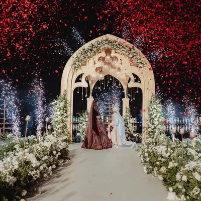 The climax of the Varmaala ceremony, as a shower of red petals and a burst of cold pyrotechnics envelop the couple. We designed this moment to be a spectacular, unforgettable celebration of their union on the over-water stage.