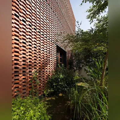 The soft, organic forms of the plants and trees provide a beautiful contrast to the rigid, geometric pattern of this building's brick facade. This is an example of how landscaping can soften and enhance modern architecture.