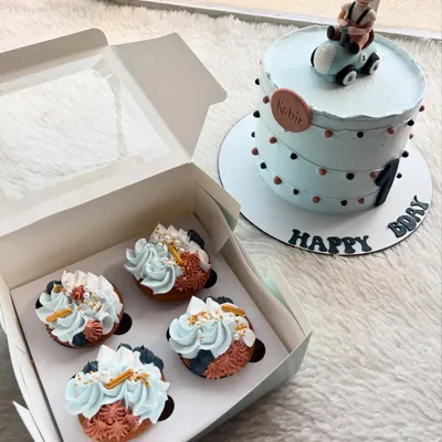A cute first birthday cake with a fondant caricature of the birthday boy in a car. The order also included matching cupcakes with a blue and coral color scheme.