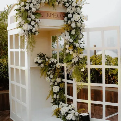 Our bespoke audio guestbook, housed in a classic white telephone booth adorned with flowers. This unique feature allows guests to leave voice messages, creating a cherished audio keepsake for the couple.