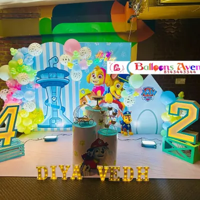 An action-packed Paw Patrol themed birthday party. This setup includes a large backdrop with the Lookout Tower, character cutouts of Skye, Chase, and Marshall, and large illuminated numbers.