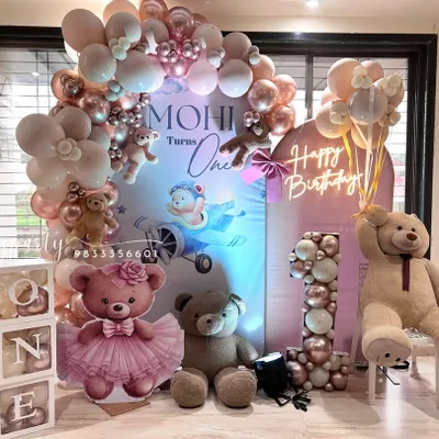 A beautiful teddy bear theme for a first birthday, featuring a soft pink and rose gold color palette. This setup includes a custom backdrop, 'ONE' letter blocks, a balloon-filled marquee number, and a 'Happy Birthday' neon sign.