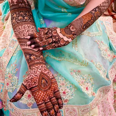 A stunning close-up of full coverage bridal mehndi. This design features a mix of floral, paisley, and geometric patterns with a beautiful teardrop motif on the palm.